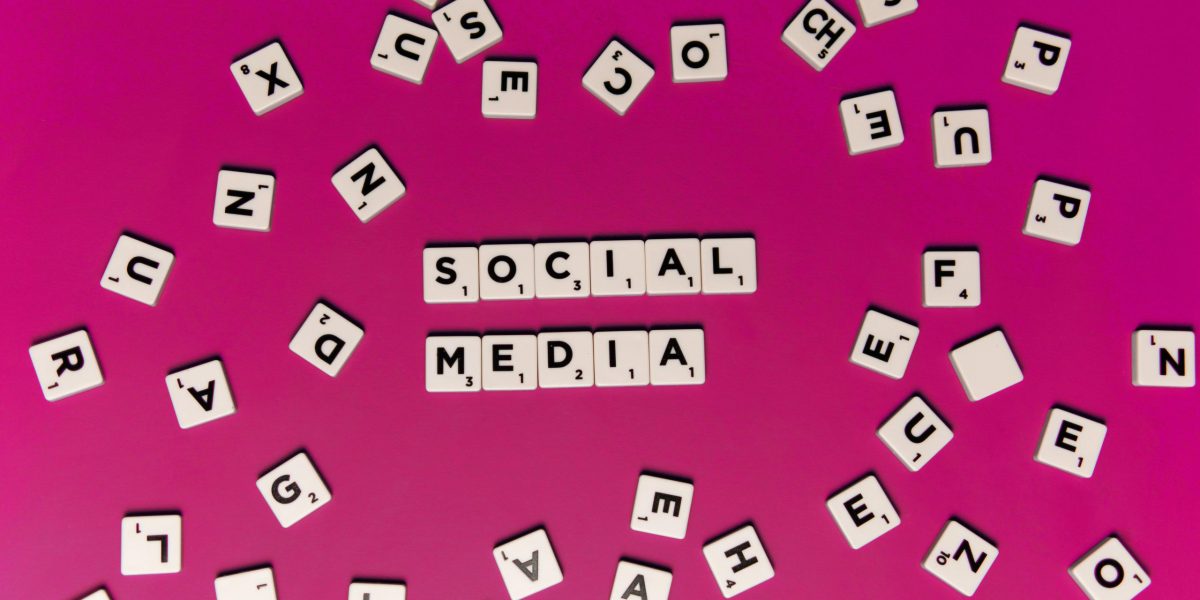 Alphabet tiles forming 'Social Media' on a vibrant pink background, perfect for digital marketing themes.